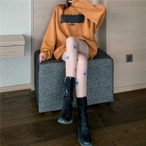 Stylish women butterfly print tights combined with casual long sleeve sweatshirt and black boots.