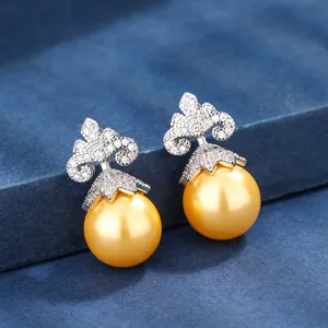 Primo piano dettagliato di eleganti orecchini di perle dorate con design superiore decorativo.