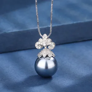 Primo piano sui dettagli della squisita ciondolo con pavé di diamanti e collana di perle scure.