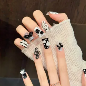 Schicke schwarz-weiße Kunstnägel mit 3D-Kamelien und Noten-Charms, elegante künstliche Nägel.
