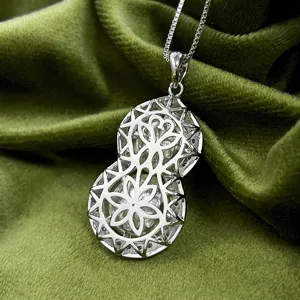 Elegant silver-toned hollow gourd pendant necklace with delicate chain on green velvet detail.