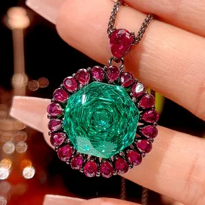 Close-up detail of luxury black gold pendant necklace with green geometric center stone and red gems.