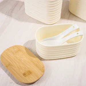 Close-up detail view of a white plastic storage box with bamboo lid and spoons on wooden table.