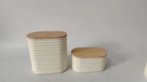 Detailed view of oval plastic storage canisters with natural bamboo lids and ribbed white bodies.