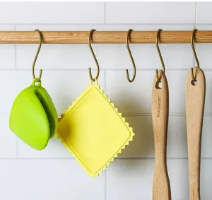 Tapis isolant en silicone et mini gant de cuisine suspendus sur la barre murale.