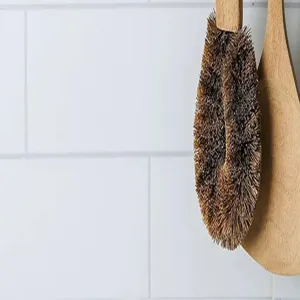 Brosse vaisselle en bois avec poils naturels suspendue au mur de carreaux blanc cuisine