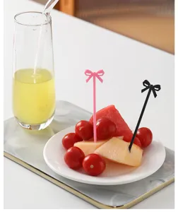 Detailansicht süßer Schleifen-Fruchtgabeln, die frisches Obst auf einem Teller spießen.