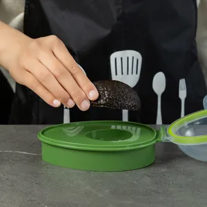 Green plastic avocado keeper container for fresh fruit storage, airtight sealed design for kitchen.