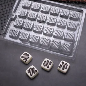 Stampo per cioccolato in PET trasparente con cioccolatini quadrati finiti, ideale per dolci.