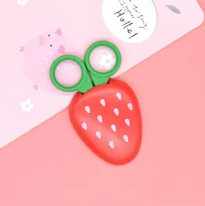 Cute strawberry safety scissors detail view, green ring handle and protective case for kids crafts.