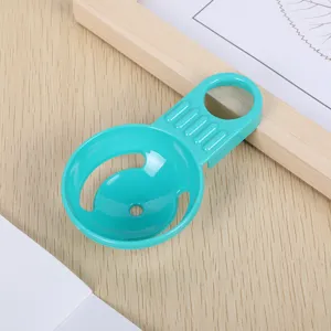 Plastic egg separator tool for kitchen baking, close-up detail shot of turquoise utility gadget.