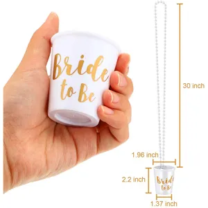 White plastic bachelorette party shot glass with pearl necklace and gold bride to be text.