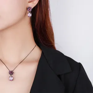 Detailed close-up of vintage black gold camellia pendant necklace and matching earrings.