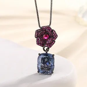 Detailed shot of vintage black gold plated camellia pendant necklace with pink and blue stones.