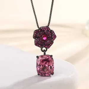 Close-up detail of black gold camellia pendant necklace with pink crystal gemstone.