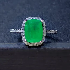 Détail de la bague en pierre précieuse verte taillée en coussin avec halo et anneau pavé.