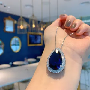 Stunning pear-shaped dark blue gemstone pendant necklace with shimmering crystal halo setting.