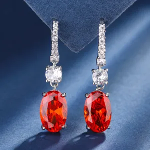 Close-up detail of elegant oval red gemstone drop earrings with sparkling cubic zirconia.