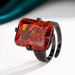 Radiant cut red gemstone ring featuring a bold black gold band and sparkling accent crystals.
