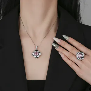 Detalle en primer plano de lujoso collar con colgante de gema rosa y anillo a juego brillante.