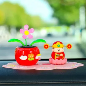 Vista detallada de la decoración solar para coche con un girasol bailarín y una simpática figura.