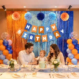 Birthday party decoration set with blue and orange tinsel backdrop, balloons and banner