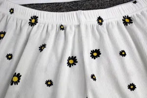 Close up view of white ribbed cotton sleepwear waist with cute black daisy flower prints.