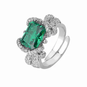 Prachtige open ring met strik van verguld koper en groene smaragd cut zirkoon steen.