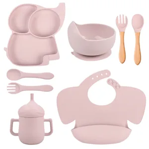 Kit de repas bébé en silicone rose avec assiette éléphant, bol, cuillères, tasse et bavoir.