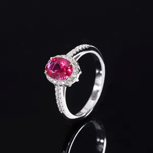 Gros plan détaillé de la superbe bague avec pierre rouge ovale et halo de zircones scintillantes.