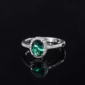 Détail de bague élégante avec pierre précieuse verte et halo de zircons scintillants.
