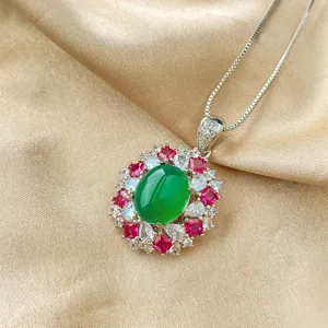 Stunning oval green cabochon pendant necklace with vibrant red and clear stone halo design.