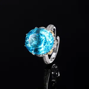 Close-up view of a large blue gemstone ring featuring sparkling pavé set rhinestones on band.