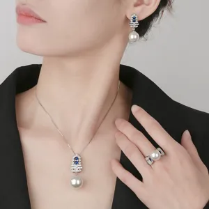 Detail view of elegant pearl jewelry set featuring Christmas tree design with blue stones.
