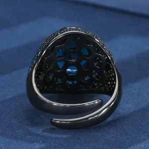 Detailed view of black gold tone open ring featuring blue synthetic gem and honeycomb back.