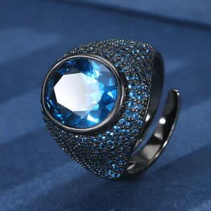 Detailed view of black gold plated oval blue gemstone statement ring with pavé small stones.