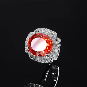 Elegante anello da donna con gemma rossa ovale e alone di diamanti scintillanti incastonati.