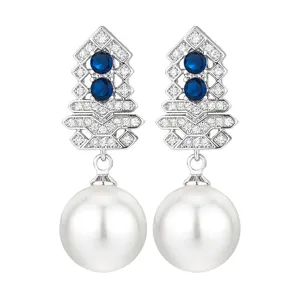 Close-up detail of elegant silver-tone geometric earrings with blue stones and large white pearl.
