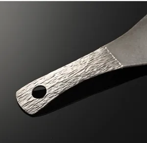 Close-up detail of pure titanium rice paddle handle with unique tree bark texture and hanging hole.