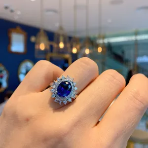 Vintage oval blue gemstone ring with sparkling diamond halo, elegant finger jewelry detail.