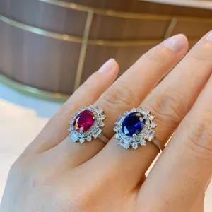 Vintage oval ruby and sapphire gemstone cluster ring set with sparkling zirconia halo details.