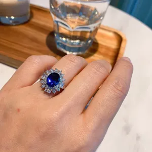 Vintage oval blue gemstone ring with sparkling zircon halo, elegant women's jewelry.