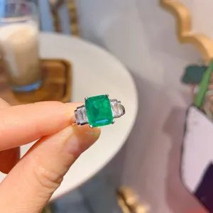 Elegante anello con gemma verde taglio smeraldo e pietre laterali per eleganza di moda donna.