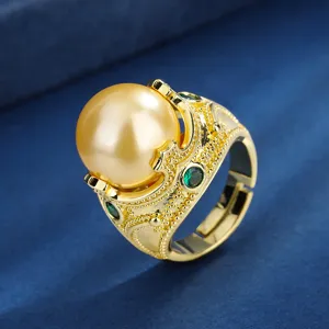 Detailopname van vintage vergulde ring met een grote gouden parel en groene accentstenen.