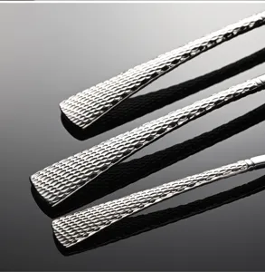 Dettaglio manico posate in acciaio inox, design coda di pesce con texture a rete martellata.