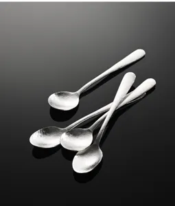 Gros plan sur des mini cuilleres a epices en metal avec finition martele, compactes.
