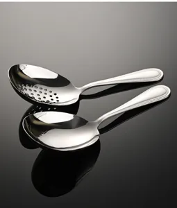 Dettaglio di cucchiaio forato e da portata in acciaio inox con elegante decorazione perlata.