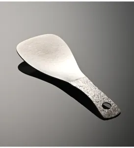Close-up detail of the pure titanium rice paddle showing the unique wood grain handle and crystal texture.