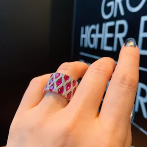 Primer plano detallado del anillo de rubí con malla ancha, diamantes y piedras rojas.