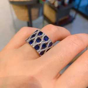 Detalle en primer plano del anillo ancho vintage con piedras azules brillantes y cristales.
